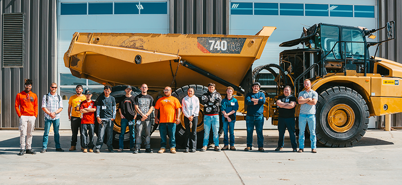 Students out on a field trip, they are standing in front of a large yellow vehicle